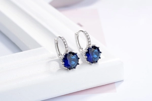 Macro view of silver hoop earrings with deep blue zircons and white pavé accents