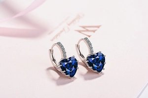 Detail of silver heart earrings featuring deep blue heart-cut zircon and pave settings