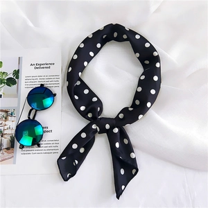 Close-up of a black satin neck scarf featuring large white polka dots and a silky texture