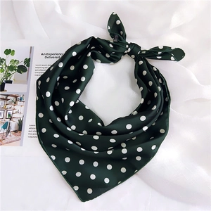 Detail of a dark green polka dot silk scarf tied on a white fabric background