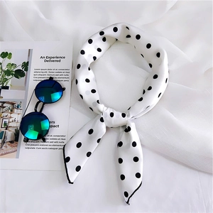Polka dot silk scarf with black edge detail on elegant white fabric background