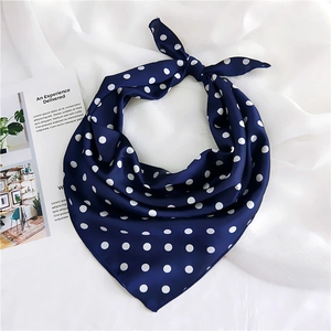 Detail of navy blue polka dot silk scarf tied on white fabric background