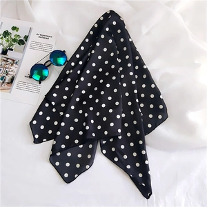 Close-up of elegant black and white polka dot silk scarf with sunglasses and magazine