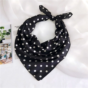 Close-up of knotted polka dot silk scarf with elegant satin finish on white fabric