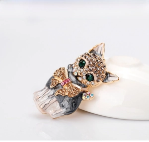 Close-up of cat brooch with green crystal eyes and enamel detail on white porcelain