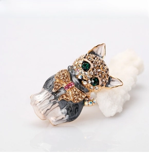 Detailed macro view of a kitten brooch with green crystal eyes on a coral display stand