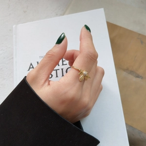 Macro shot of gold bee ring with sparkling white zircon details on a model's hand