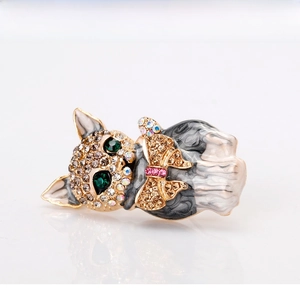 Detail of a cat brooch featuring green rhinestone eyes and pink enamel bowtie on gold-plated alloy