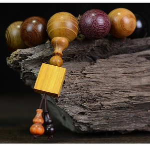Macro shot of multi-colored wooden prayer beads with gourd pendant on weathered wood