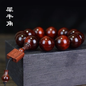 Polished dark red sandalwood beads bracelet displayed on zen style charcoal base
