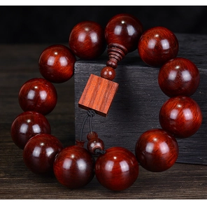 Macro view of deep red lobular red sandalwood prayer beads on a black wooden stand