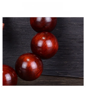 Macro shot of polished sandalwood beads showing dark grain texture and glossy finish