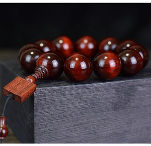 Macro shot of polished red sandalwood beads on a textured dark wood display case