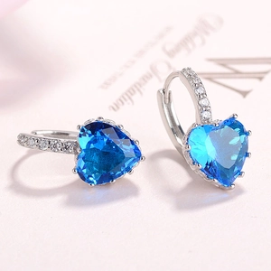 Detail of silver heart-shaped earrings with dark blue gemstone and white zircon stones