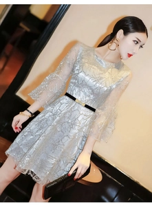 Close-up of golden square buckle on thin black elastic belt over silver sequin lace dress