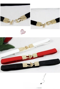 Close-up of slim elastic waist belts with golden metal buckles in black, white, and red