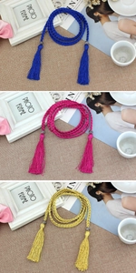 Close-up of woven rope waist belts with long tassels in blue, rose red, and yellow
