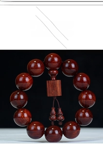 Macro detail of red sandalwood beads with carved gourd pendants and polished wood texture