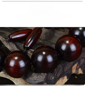 Macro shot of polished red sandalwood beads with natural grain and a vintage wood background