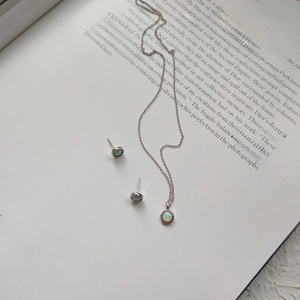 Elegant S925 sterling silver opal jewelry set with round necklace and stud earrings on a book