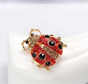 Close-up of golden ladybug brooch with vibrant red and black faceted rhinestones