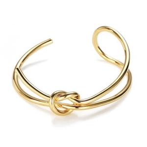 Detailed view of the gold-plated knot bracelet with adjustable open cuff design