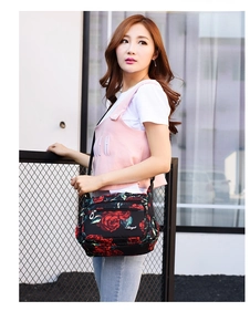 Detailed view of women's floral nylon crossbody bag with red rose patterns and zipper pockets