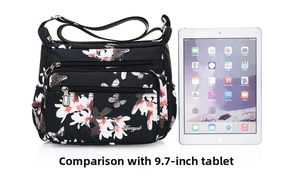Black nylon floral crossbody bag size comparison with a 9.7-inch tablet computer