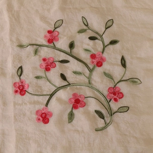 Close-up of floral embroidery with pink and red flowers on a beige chiffon scarf
