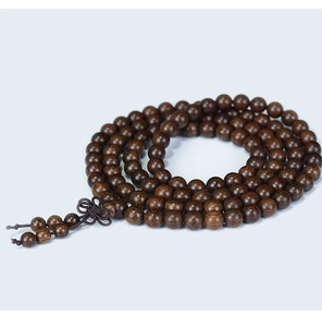 Macro detail of dark brown sandalwood Buddhist beads with natural wood grain and tassel