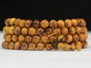 Gros plan de 108 perles de bois de santal montrant le grain naturel et la texture polie