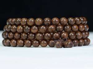Close-up of four-layer dark brown sandalwood prayer beads with traditional Chinese knot tassel