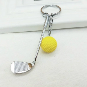 Detail of creative golf club keychain with vibrant yellow ball on textured background