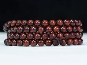 Macro shot of 108 high-density sandalwood beads with deep red texture and polished finish