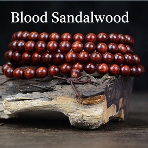 Polished blood sandalwood 108 prayer beads bracelet on weathered wood background