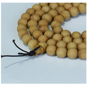 Macro shot of 108 Thuja beads showing natural wood grain and brown cord knot detail
