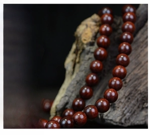 Macro shot of 108 polished sandalwood beads with natural grain on a rustic wood base