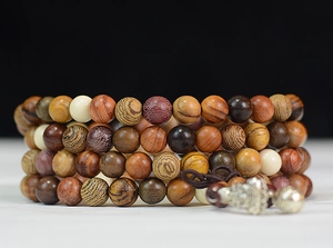 Detail of 108 wooden prayer beads showing natural grain and metallic charm accents