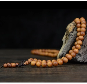 Detail of 108 sandalwood prayer beads displayed on natural withered wood backdrop