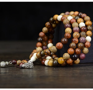 Close-up of multicolored 108 wooden prayer beads with a silver Buddha charm and gourd pendant