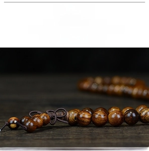 Macro shot of polished black rosewood prayer beads showing rich texture and glossy finish
