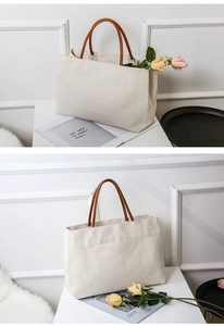 Detail of minimalist cream canvas tote bag with brown leather handles on a white background