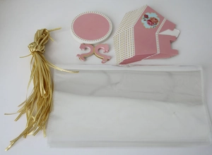 Flat lay detail of pink party favor kit with gold ribbons, floral cards and treat bags