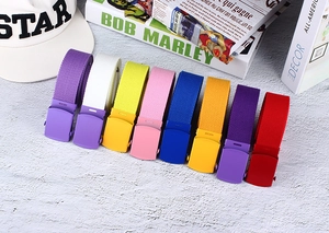 Flat lay of colorful nylon canvas belts with matte buckles next to fashion books