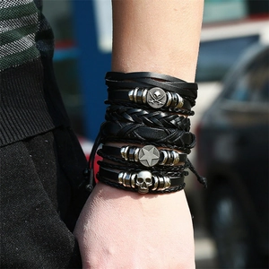 Close-up of vintage multilayer braided leather bracelets with silver skull and star charms