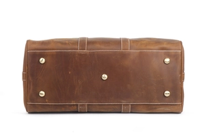 Detail of crazy horse leather bag bottom with five protective metal feet and white stitching
