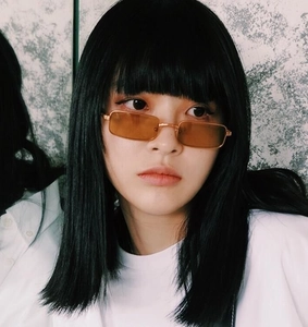 Detalle de gafas de sol cuadradas en metal dorado con lentes naranjas en modelo mujer