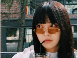 Primer plano de una modelo con gafas de sol rectangulares retro, montura dorada y lentes naranja