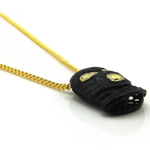 Macro shot of hiphop pendant with black balaclava mask and diamond eyes on gold cuban chain