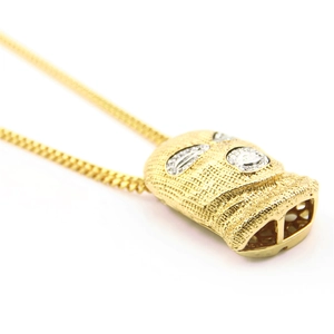 Close-up of golden hip-hop ski mask pendant with iced-out rhinestones on Cuban link chain